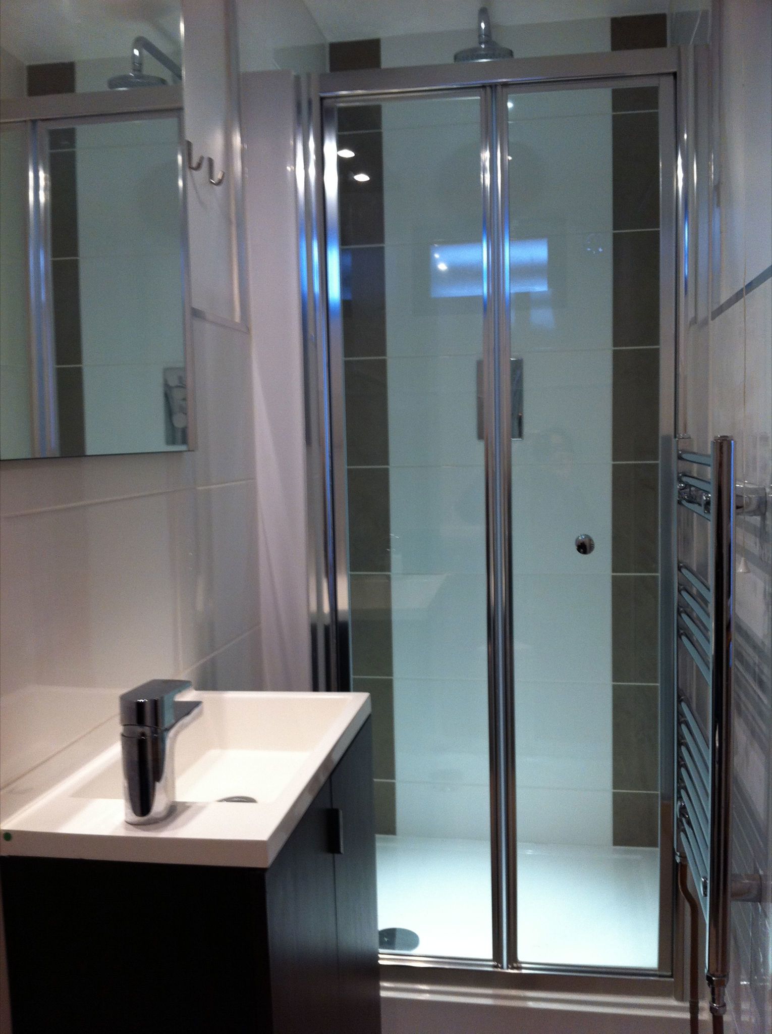 A modern bathroom with a glass-enclosed shower, a white sink, and a mirror.