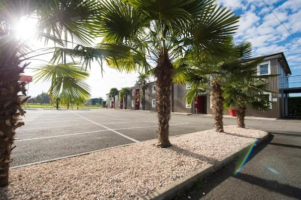 Un estacionamiento con palmeras y un edificio de diseño moderno.