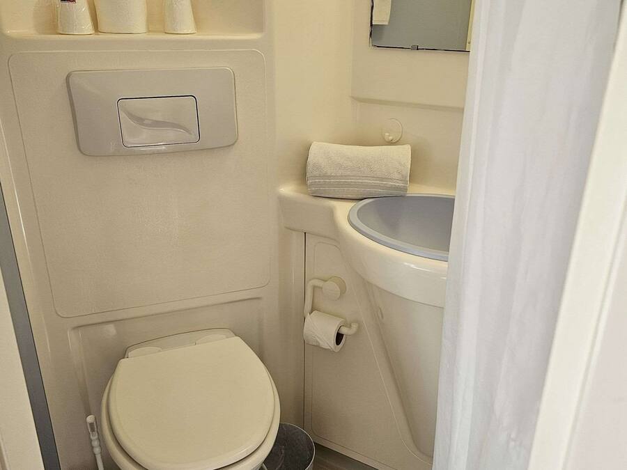 Un baño pequeño y funcional con inodoro, lavamanos y espejo.