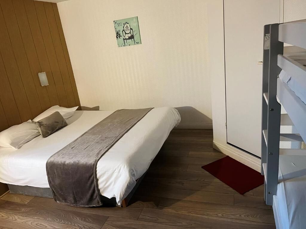 A bedroom with a bed, a wooden wall, a white door, and a small artwork on the wall.