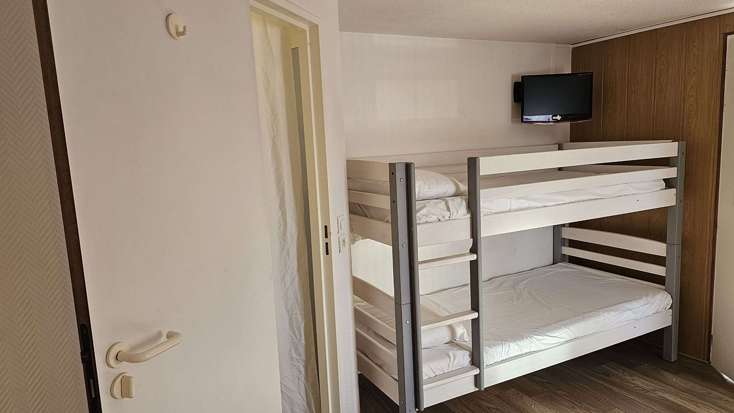 A bunk bed room with a television mounted above it.