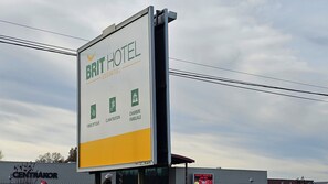 Cartel publicitario de Brit Hotel, con servicios como fibra óptica, control de clima y habitaciones familiares.
