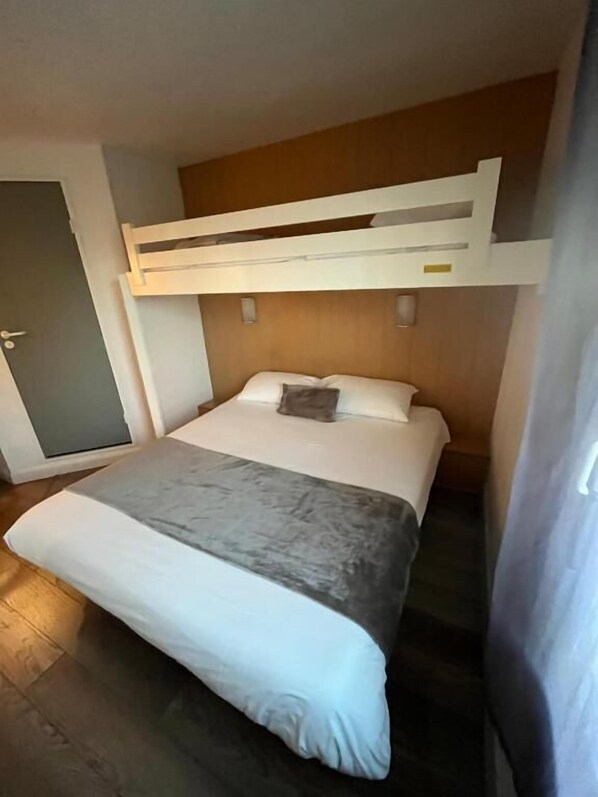 A bunk bed with a wooden headboard, a white mattress, and a grey blanket. - Brit Hotel Essentiel Pau Lescar (Lescar)