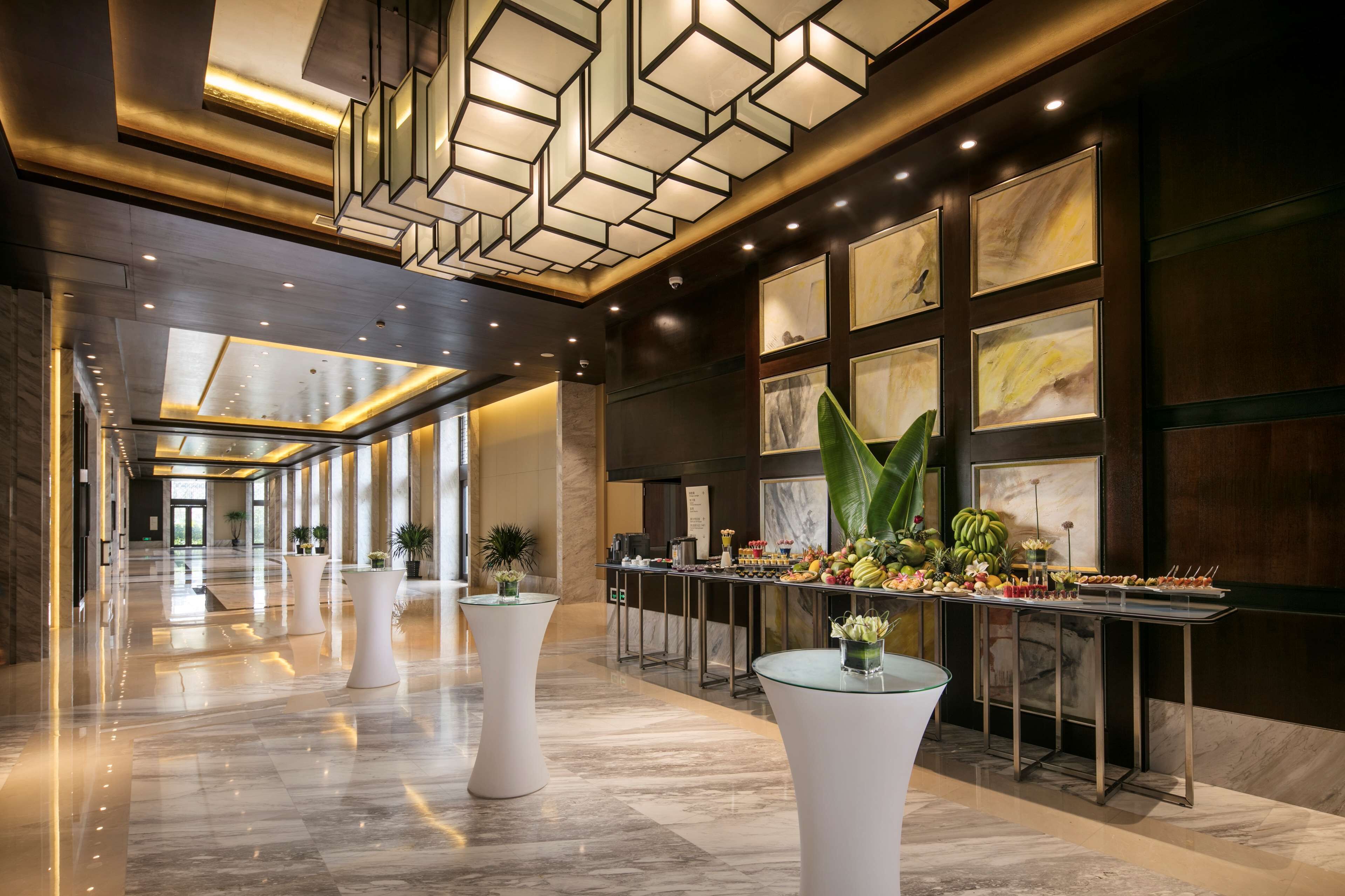A spacious lobby with a long reception desk, modern lighting, and a marble floor.