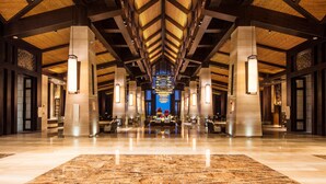 Een ruime lobby met een hoge plafond, grote zuilen en een centrale zithoek.