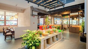 A restaurant with a thatched roof, indoor plants, and a buffet counter. - Yiaihu Hotel (Huanggang)