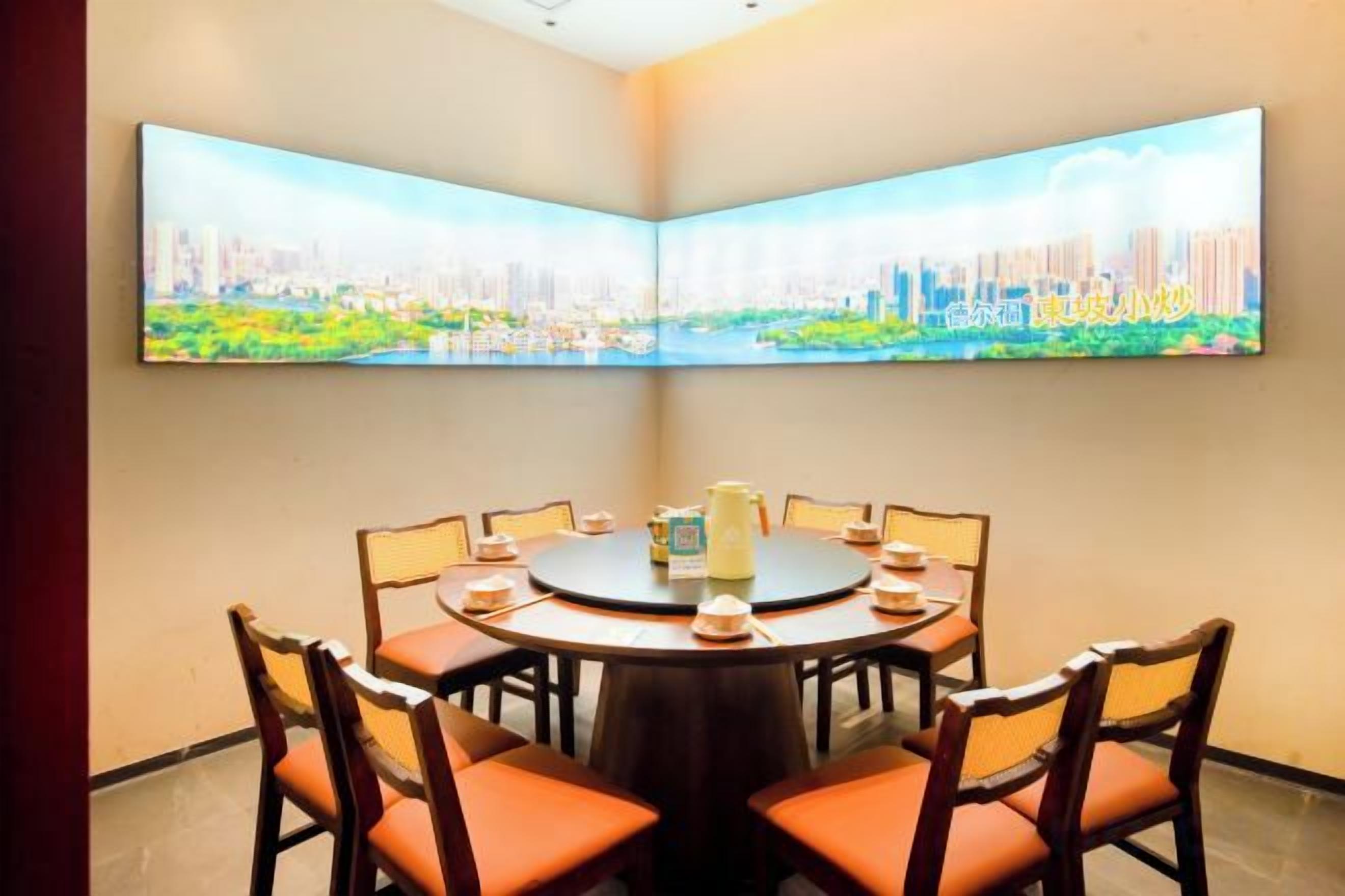 A conference room with a round table, chairs, and a cityscape painting on the wall.