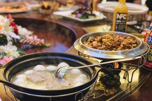 A hot pot setup with a variety of ingredients and a bottle of sauce. - Yiaihu Hotel (Huanggang)