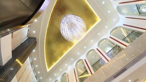 A modern interior with a central light fixture, multiple floors, and a staircase. - Yiaihu Hotel (Huanggang)