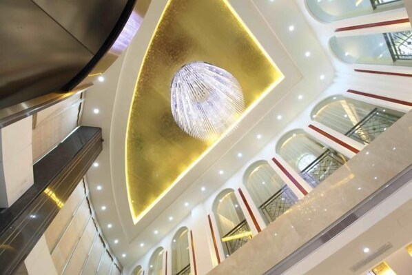 A modern interior with a central light fixture, multiple floors, and a staircase. - Yiaihu Hotel (Huanggang)
