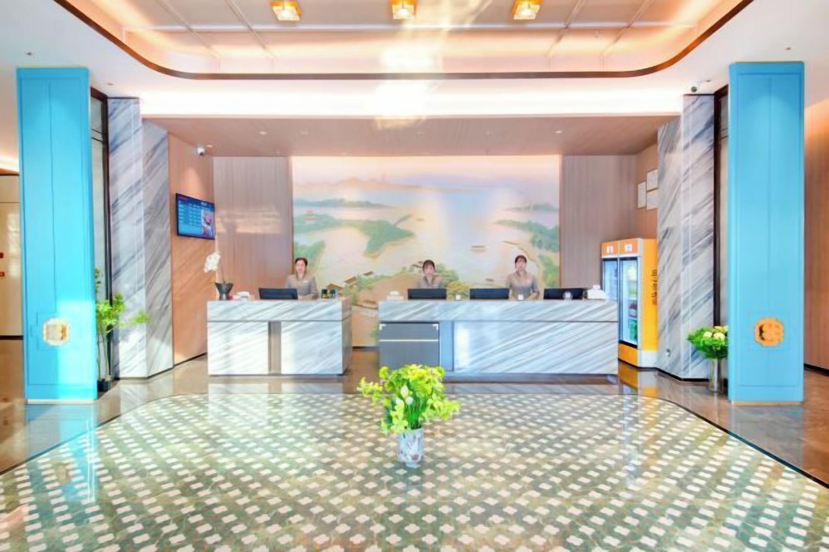 A hotel reception area with marble counters, a large reception desk, and a decorative wall mural.