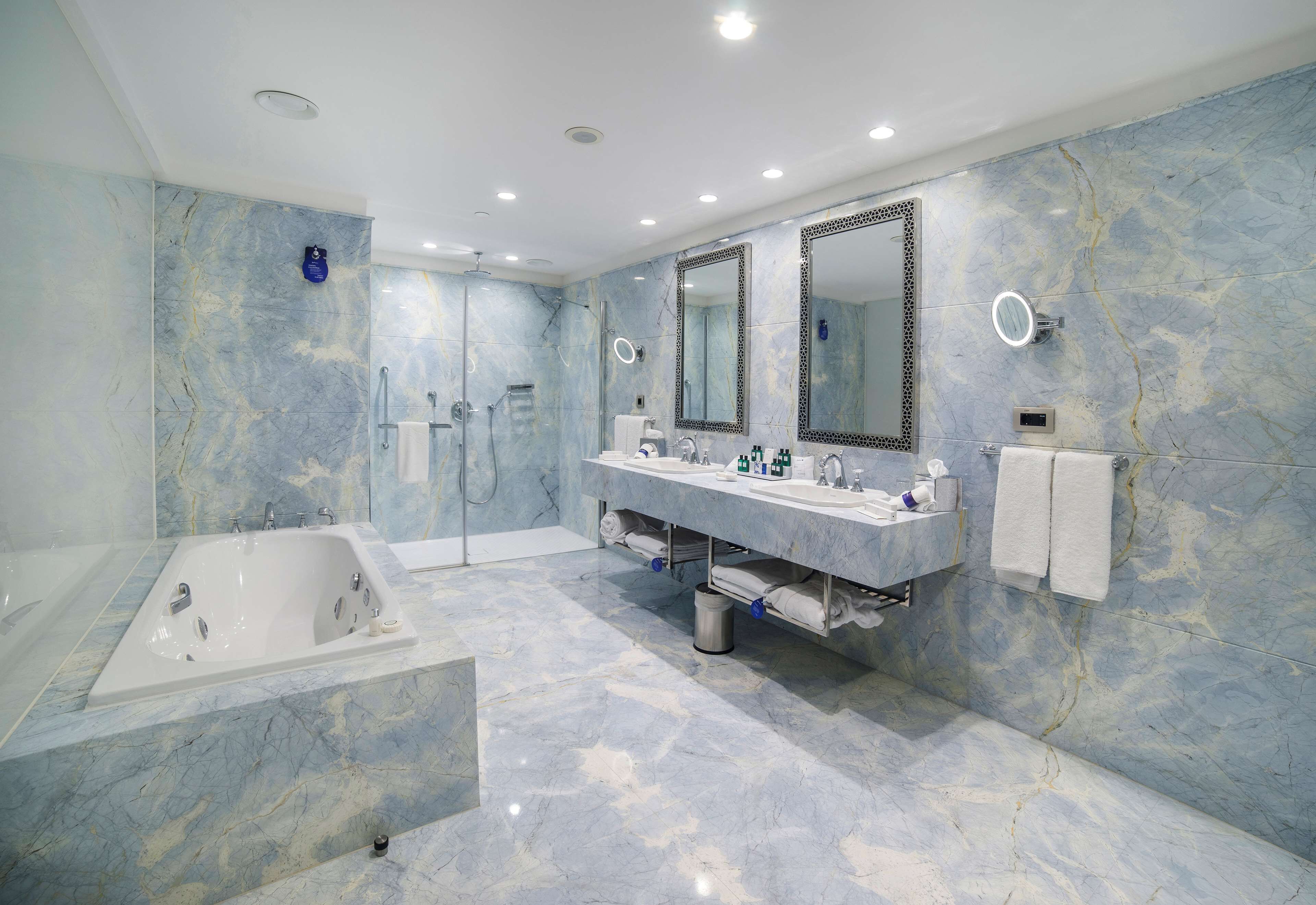 A modern bathroom with a large bathtub, two sinks, and a walk-in shower.