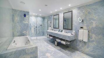 A modern bathroom with a large bathtub, two sinks, and a walk-in shower.