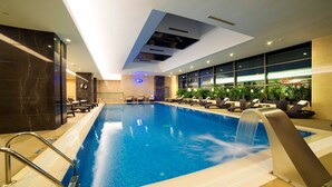 An indoor swimming pool with a waterfall feature, lounge chairs, and potted plants. - Radisson Blu Hotel, Kayseri (Kayseri)