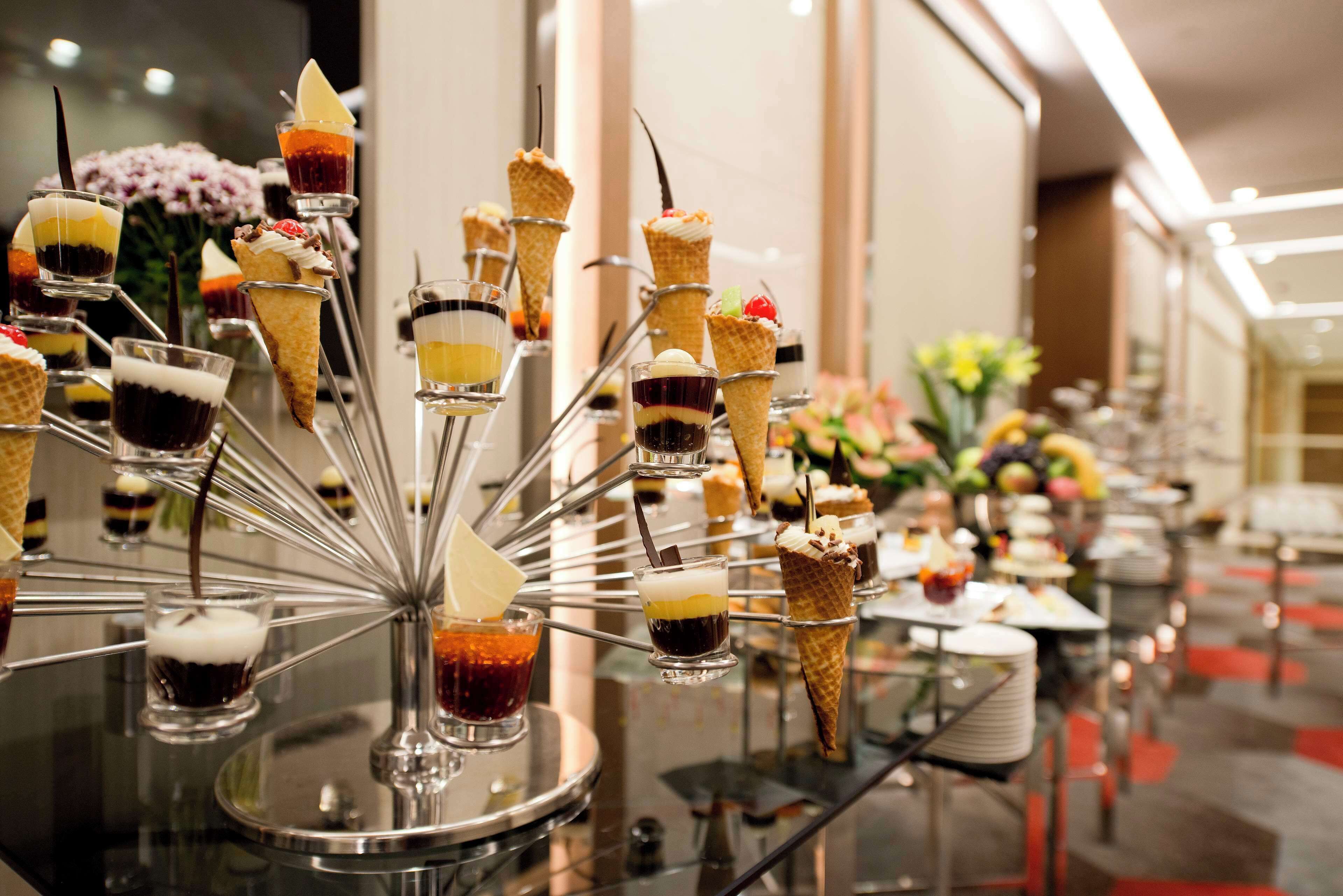 A dessert display with various ice cream cones and small glasses of beverages.