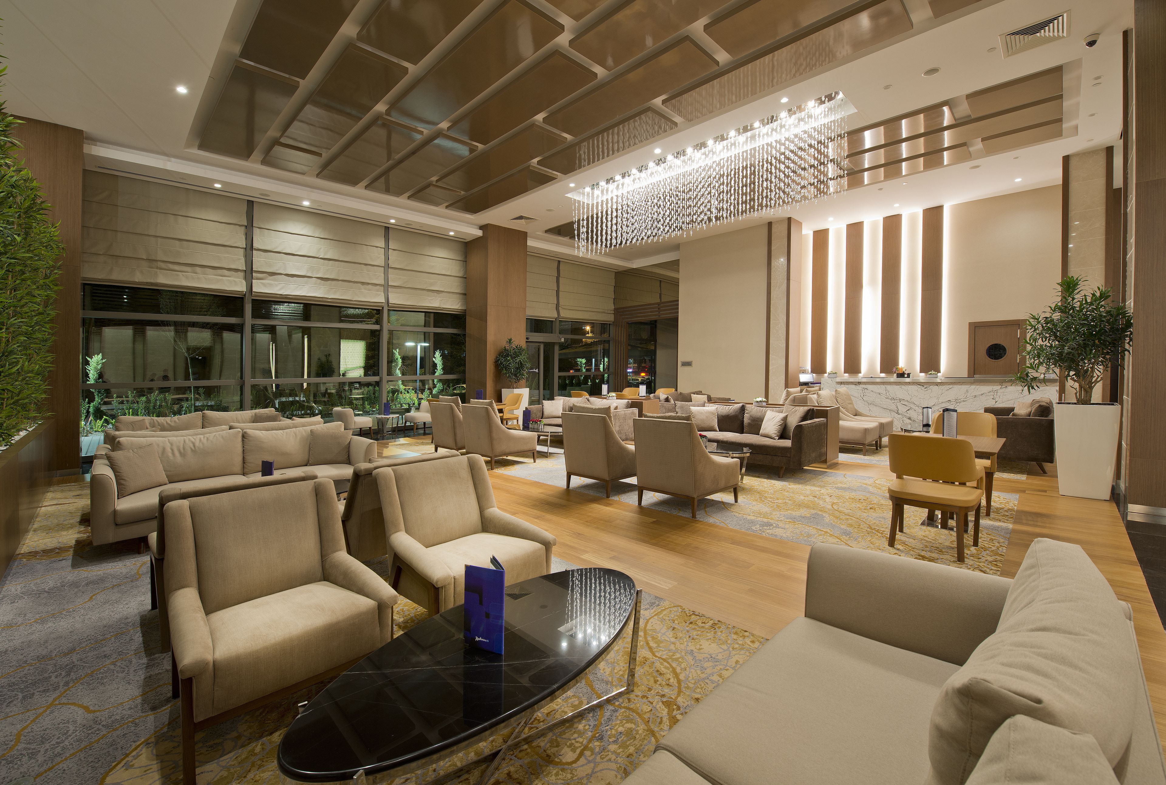 A spacious lobby with multiple seating areas, a reception desk, and a large chandelier.