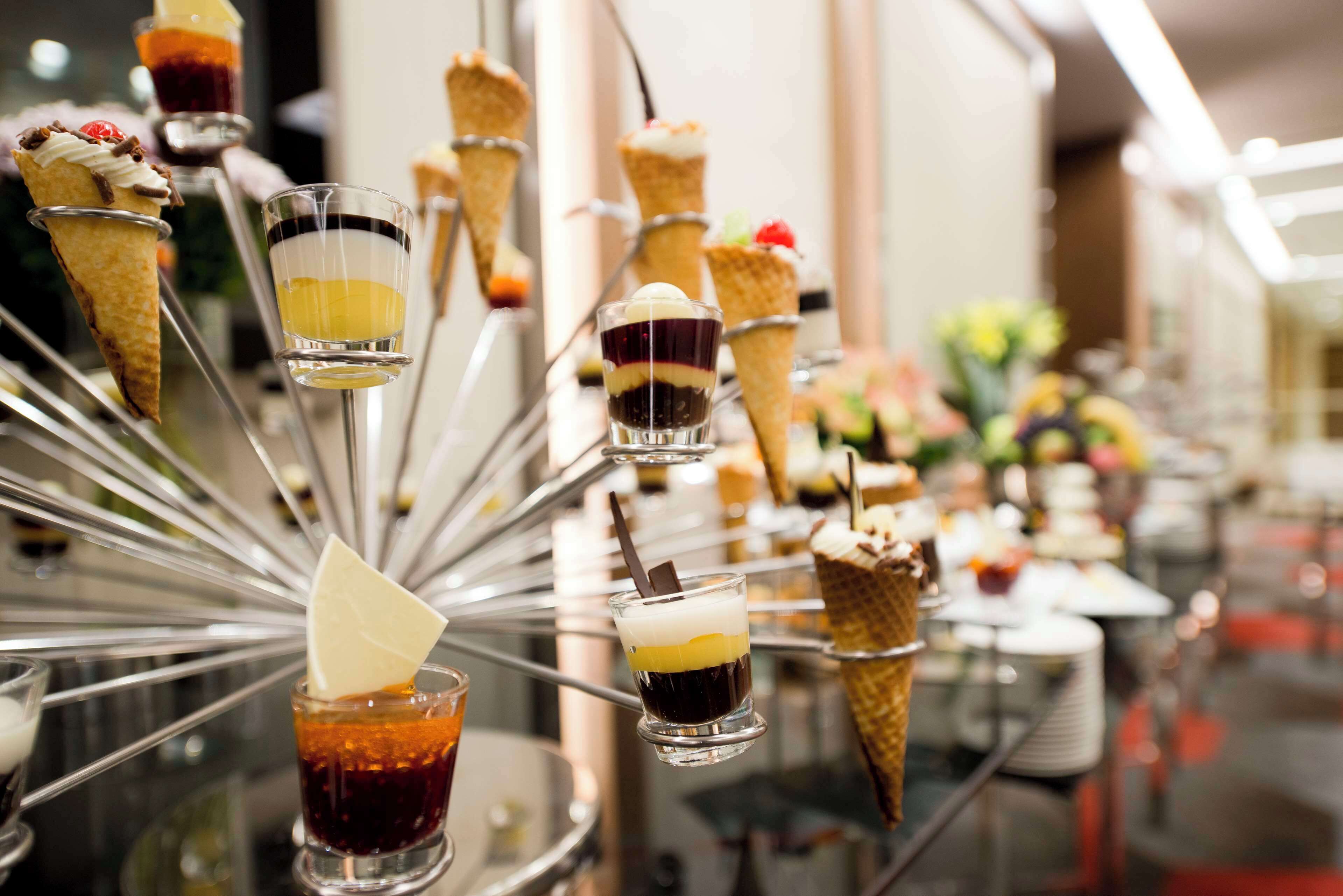 Una exhibición de postres con distintos helados en cono y pequeños vasos de postres en capas.