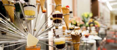 Una exhibición de postres con distintos helados en cono y pequeños vasos de postres en capas.
