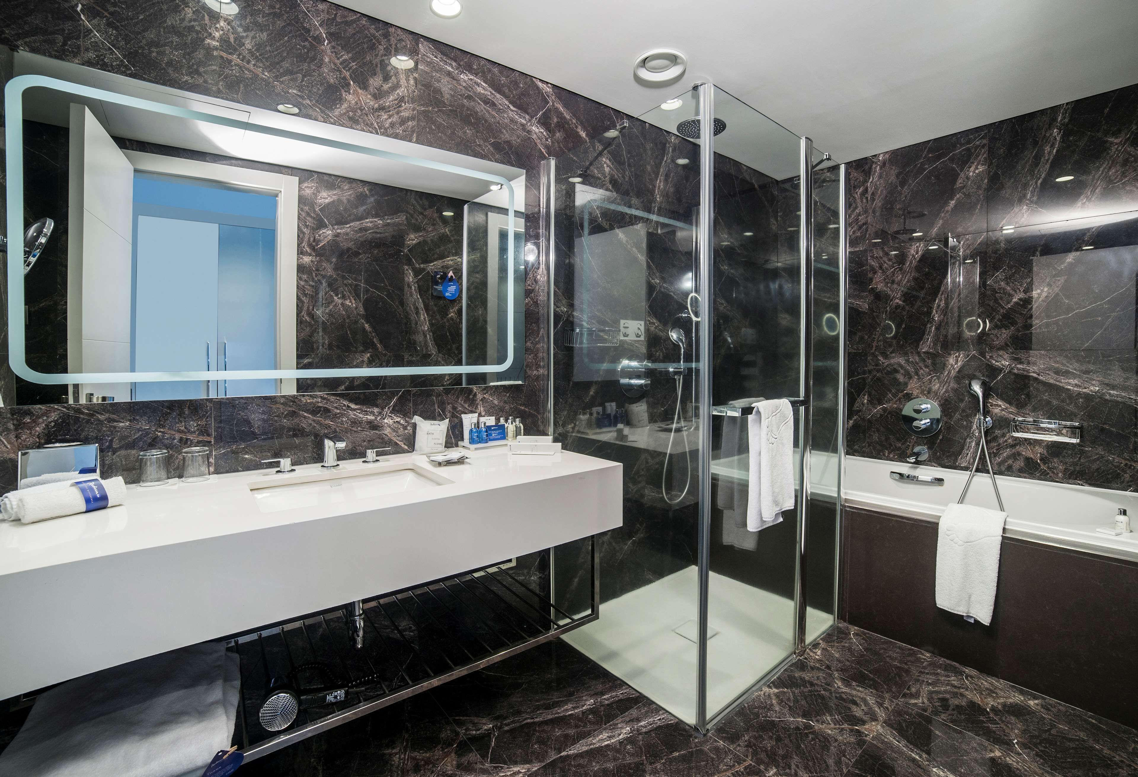 A modern bathroom with a glass-enclosed shower, a large mirror, and a white vanity.