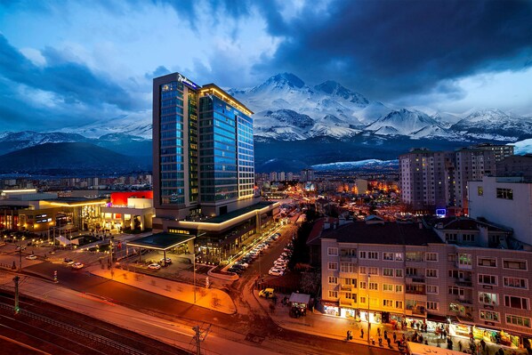Un hotel de diseño moderno, con aparcamiento y vistas a montañas nevadas al fondo.