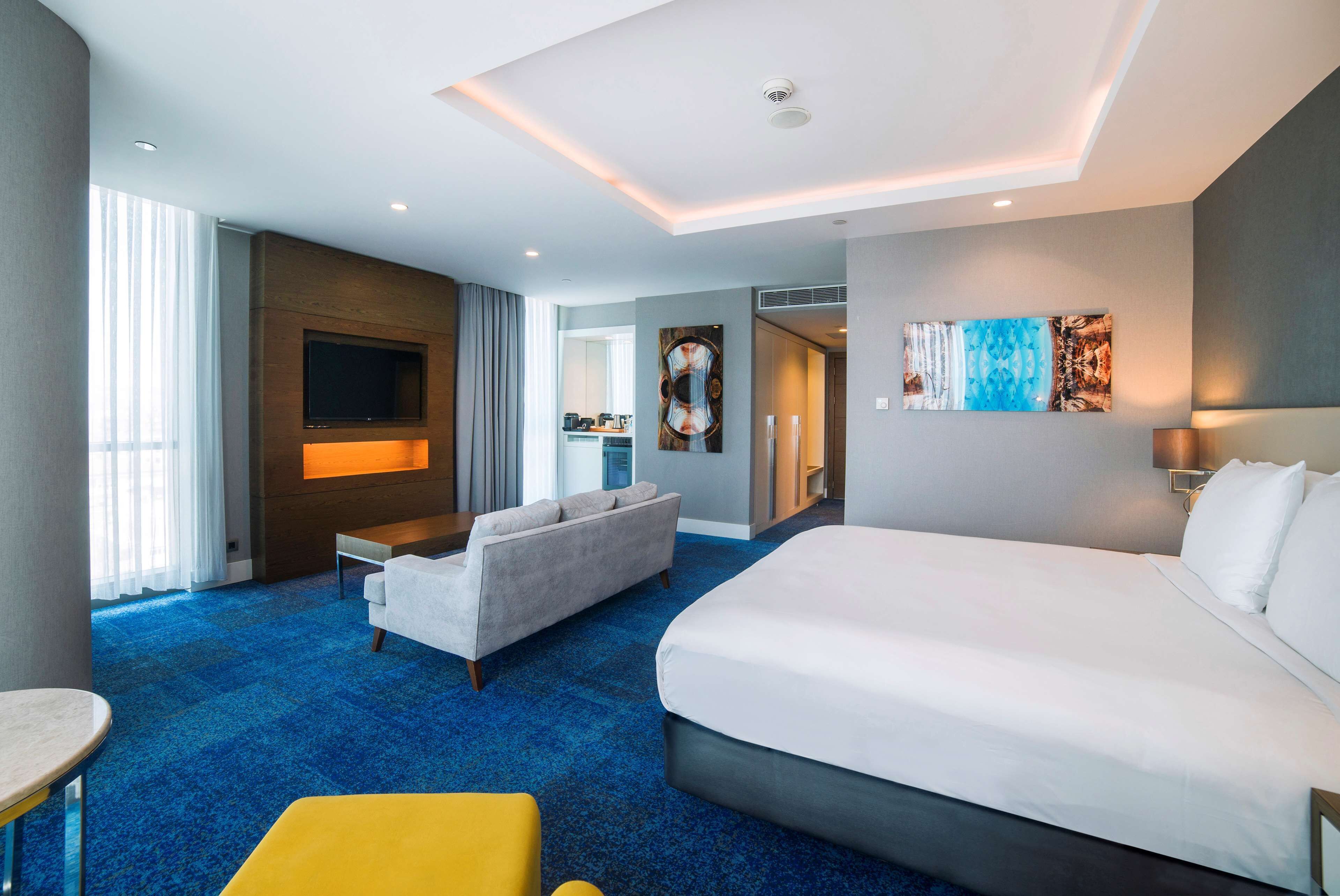 Een moderne hotelkamer met een groot bed, een bank, een televisie en een eethoek.