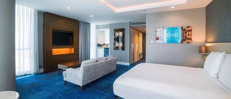 Een moderne hotelkamer met een groot bed, een bank, een televisie en een eethoek.