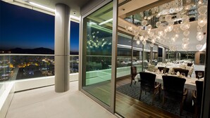 A modern dining area with a glass wall overlooking a cityscape at night. - Radisson Blu Hotel, Kayseri (Kayseri)