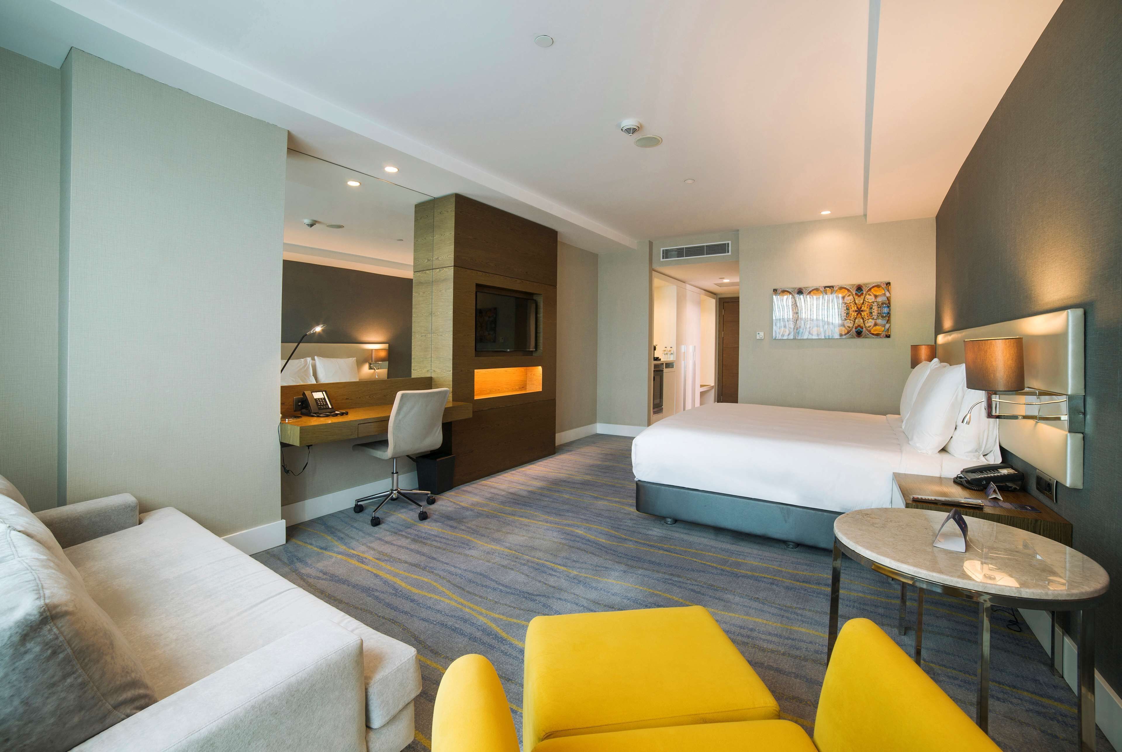 Ein Hotelzimmer mit Bett, Schreibtisch mit Stuhl, kleinem Tisch und einer Couch.