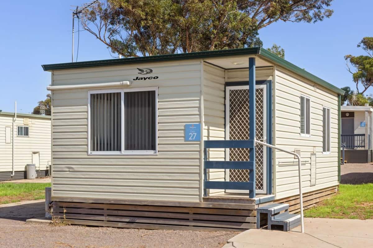 A mobile home with a number 27 sign, a covered porch, and a small front yard.