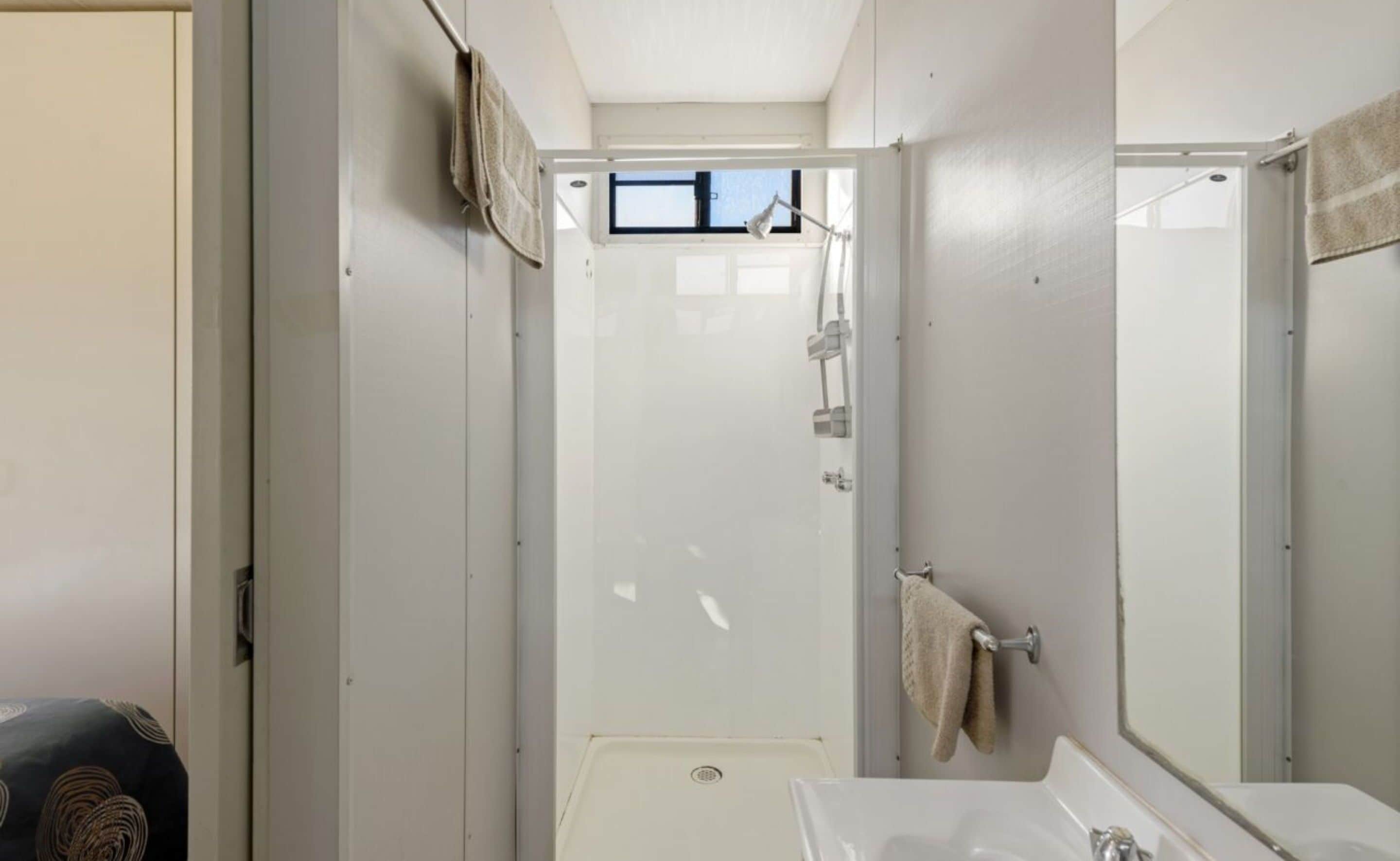 A compact bathroom with a shower, a sink, and a mirror.