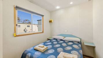 A small, single-bed room with a window overlooking a residential area.
