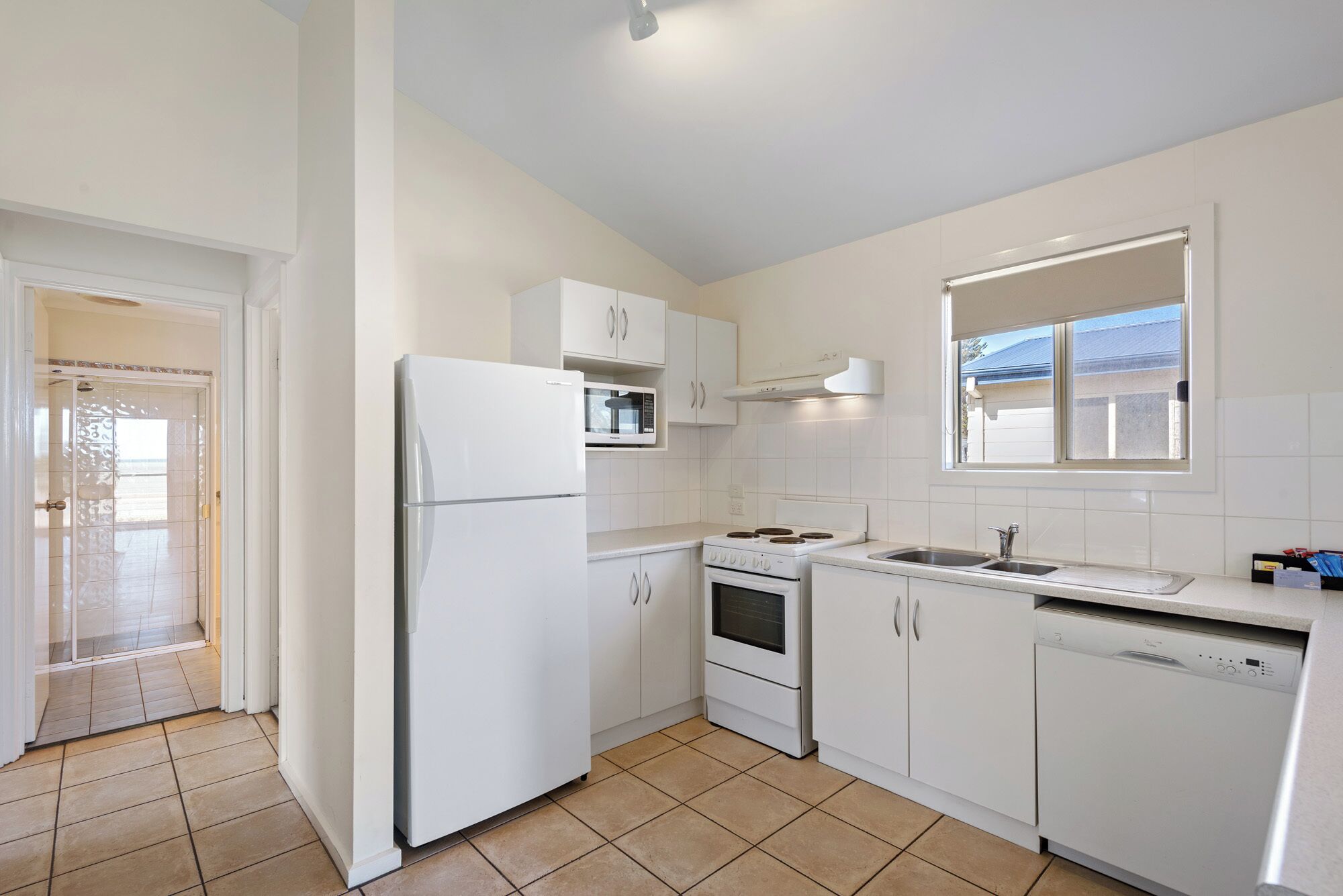 A modern kitchen with white cabinets, a built-in microwave, a stove, and a dishwasher.