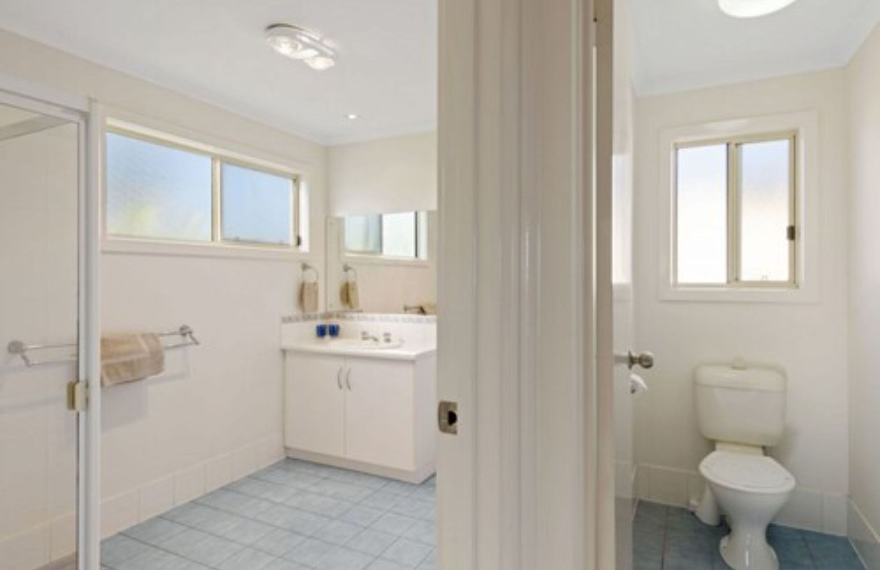 Et badeværelse med toilet, vask og spejl.