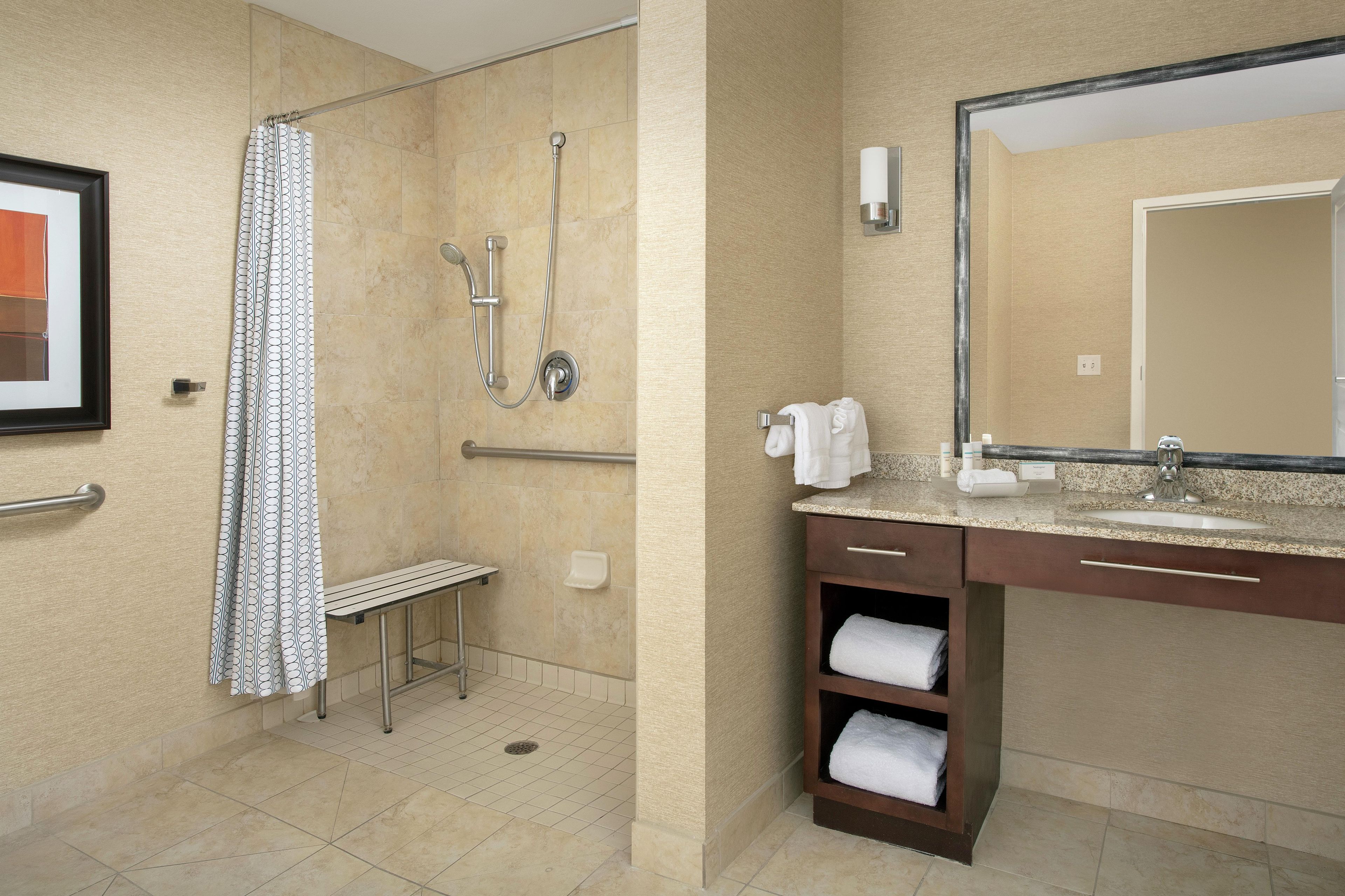 Ein Badezimmer mit Dusche, Waschbecken, Spiegel und Handtuchhalter.