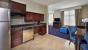 Una habitación de hotel compacta con kitchenette, televisión de pantalla plana, sofá y zona de comedor.