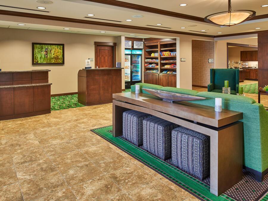 A reception area with a counter, seating, and a refrigerator stocked with beverages.