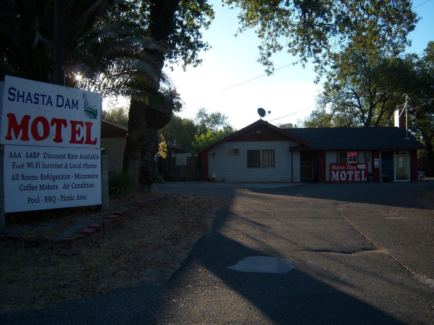 Letrero del Shasta Dam Motel con servicios indicados, que incluyen Wi-Fi gratuito, internet, teléfono local, todos los servicios de las habitaciones y una piscina.