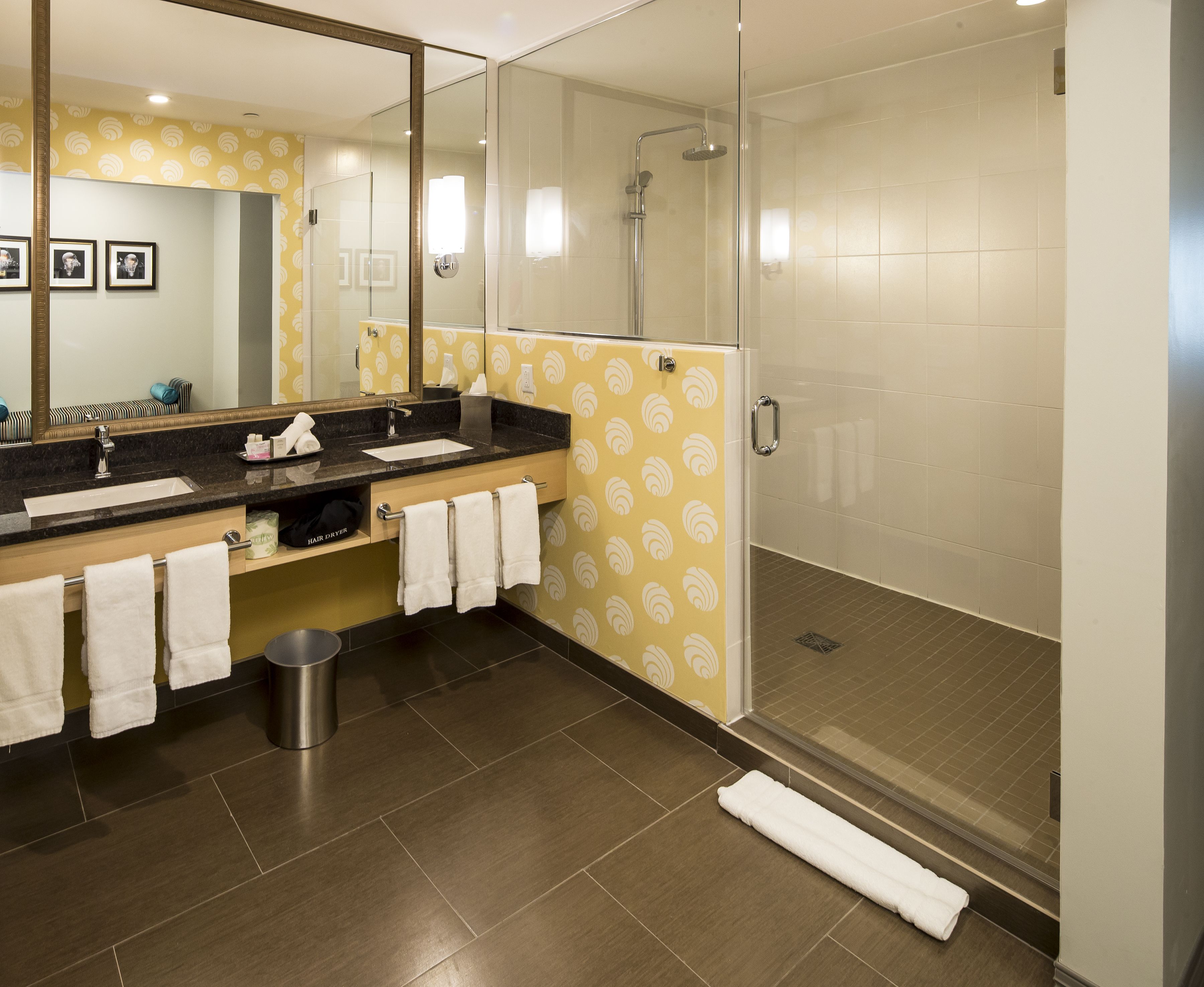 A modern bathroom with a large mirror, a sink, and a shower.