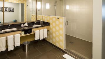 A modern bathroom with a large mirror, a sink, and a shower.