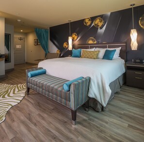 Una habitación de hotel moderna con una cama grande, un banco y una mesita de noche.