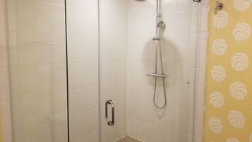A walk-in shower with a glass door, a handheld showerhead, and a handheld shower attachment.