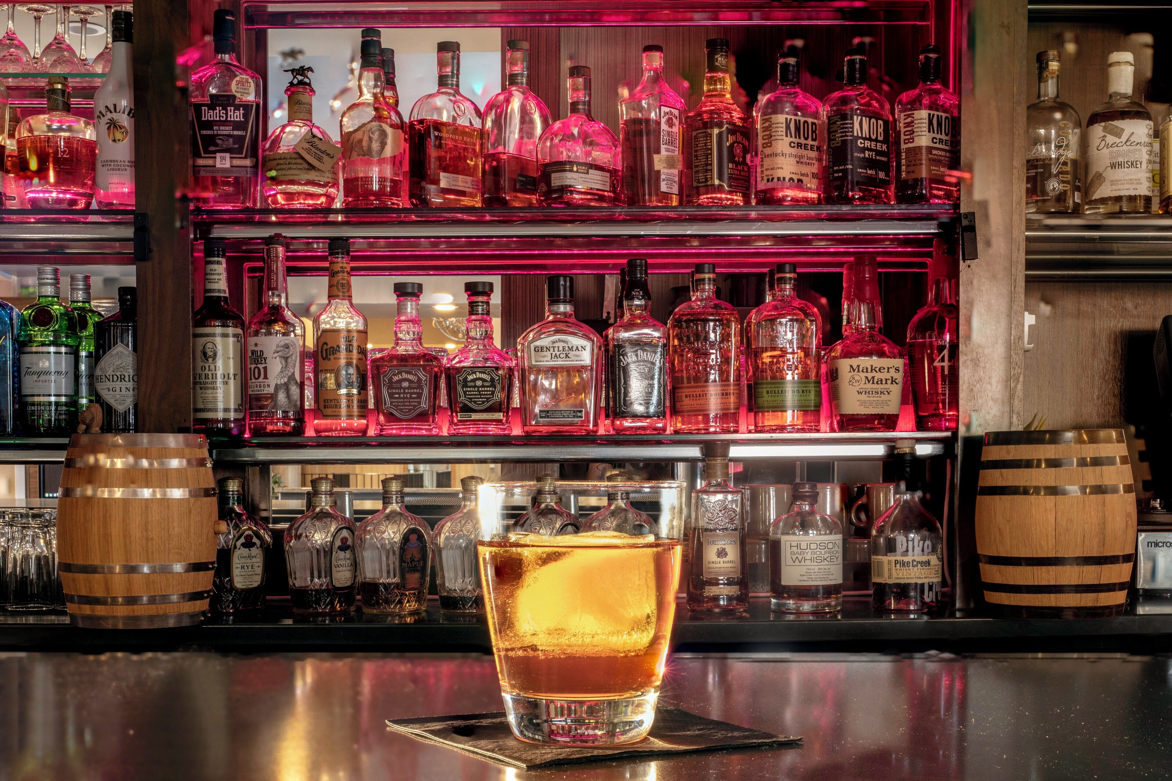 Un bar avec différentes bouteilles d’alcool et un verre de whisky.