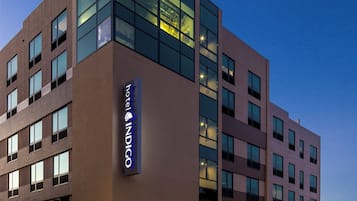 A modern hotel building with a prominent glass facade and a sign reading 'Hotel Indigo.'