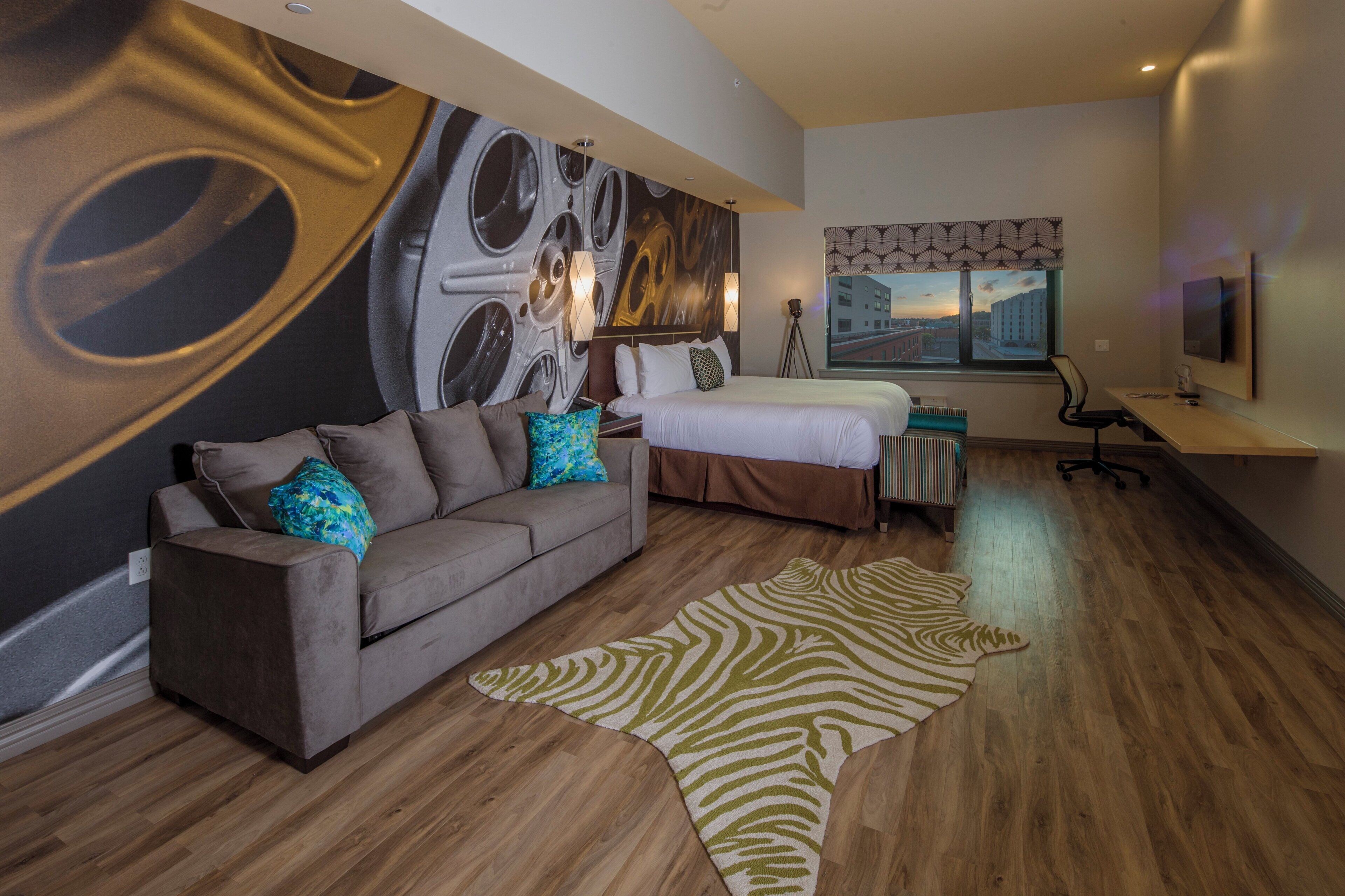 Une chambre d’hôtel moderne avec un grand lit, un canapé, un bureau et une vue sur la ville.