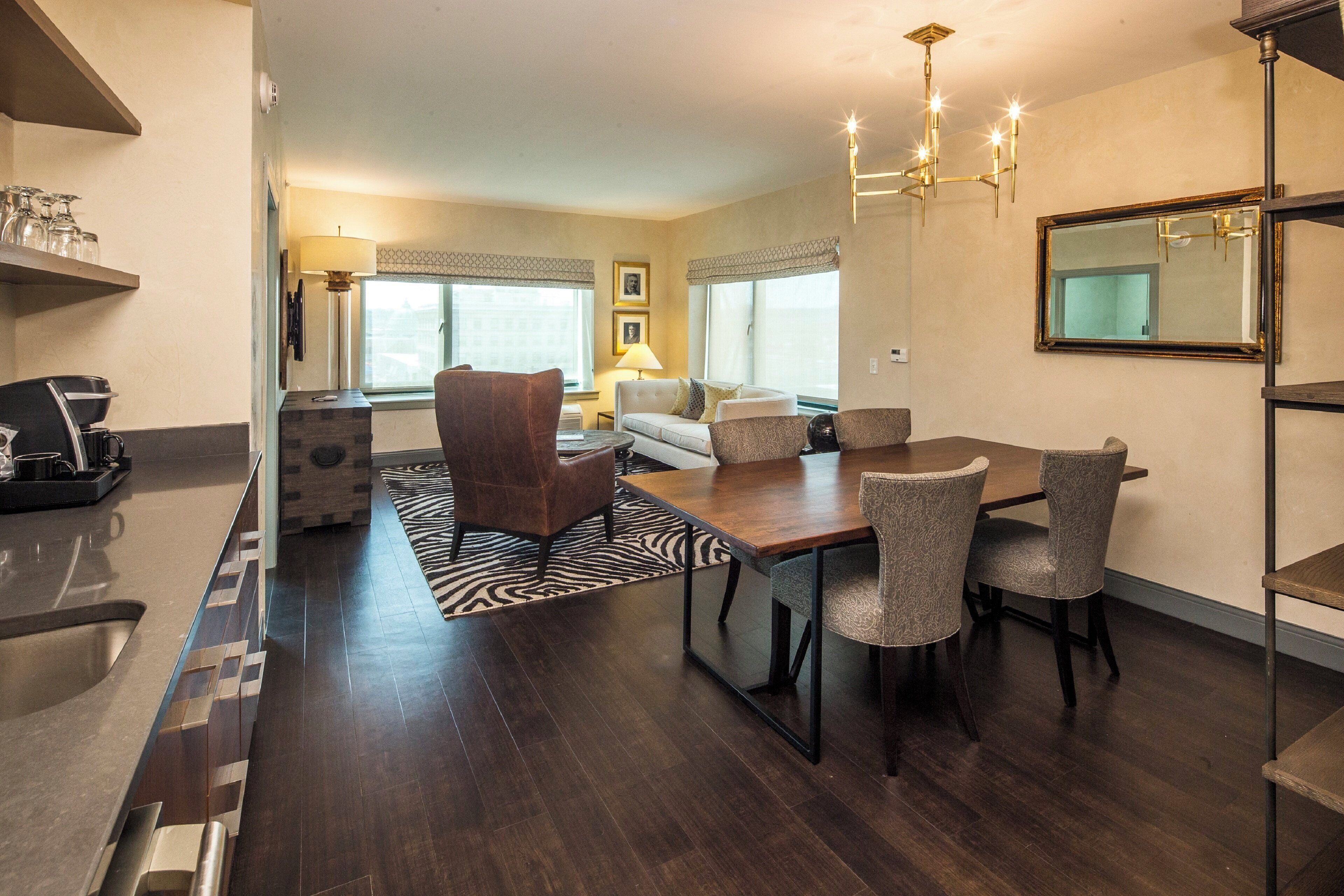 A modern living room with a dining area, featuring a sofa, chairs, a coffee table, and a chandelier.