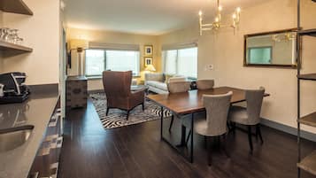 A modern living room with a dining area, featuring a sofa, chairs, a coffee table, and a chandelier.