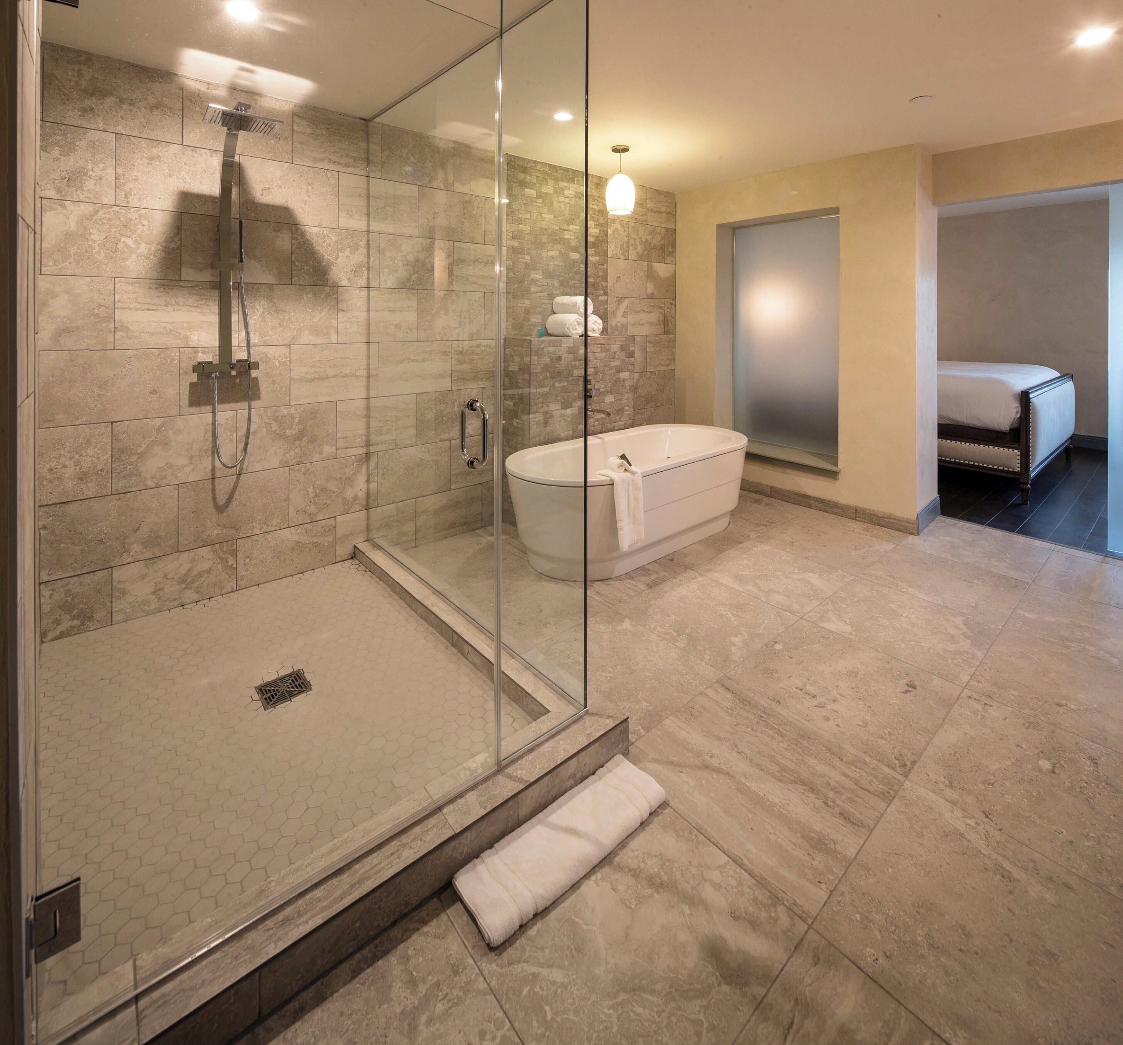 Un baño moderno con ducha de vidrio, bañera independiente y un inodoro a la vista.