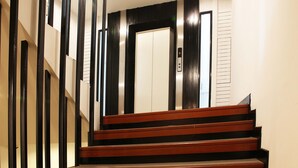 Una escalera de madera con barandillas negras que conduce a un ascensor.
