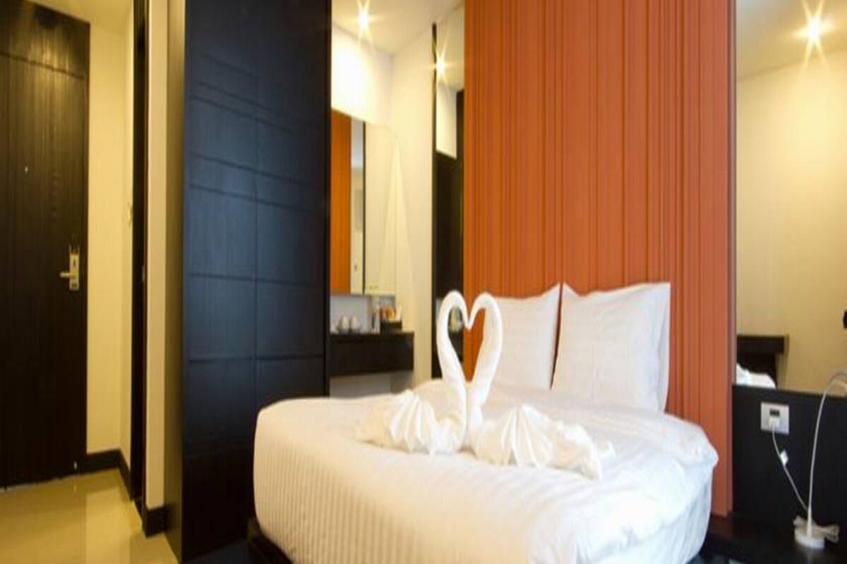 Une chambre d’hôtel avec un lit, une table de chevet, un miroir et une porte.