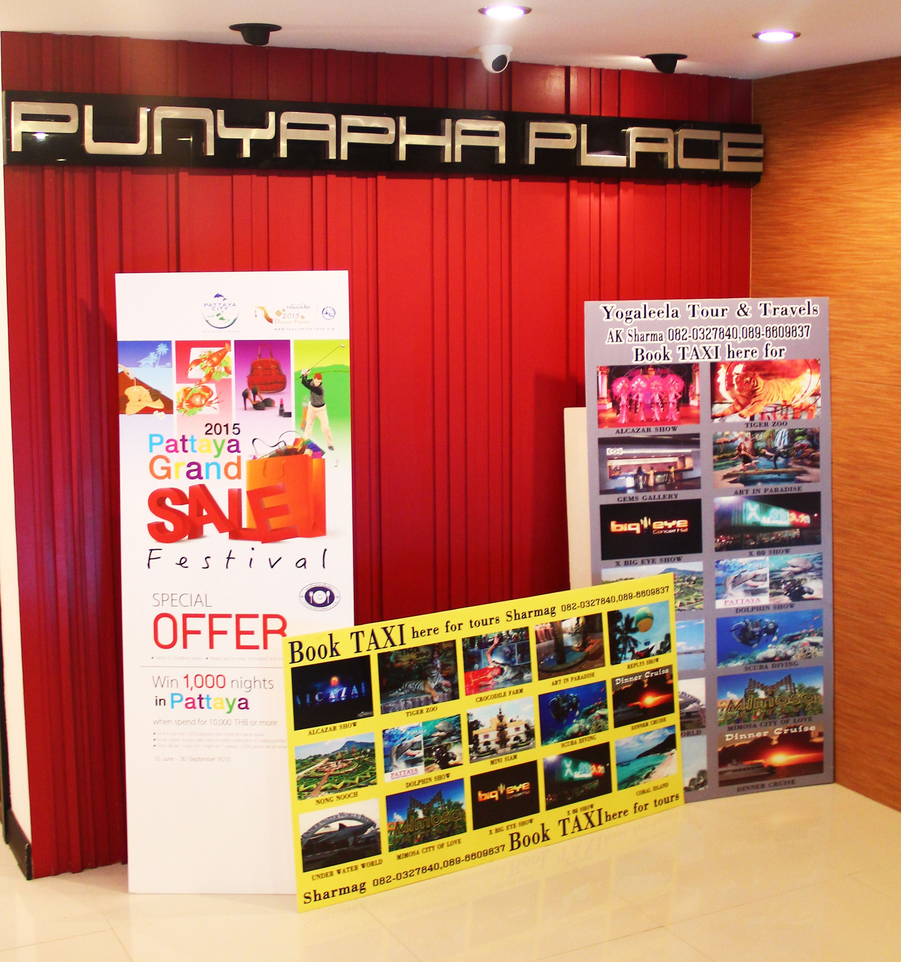 Une installation promotionnelle pour le Pattaya Grand Festival, avec un rideau rouge en arrière-plan et divers affiches annonçant les événements.